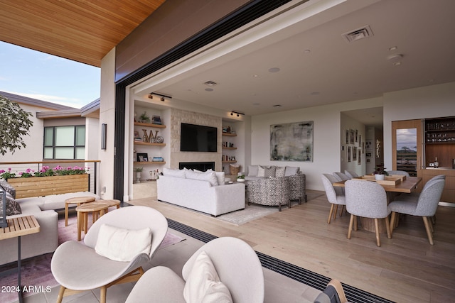 living room with wooden ceiling, built in shelves, light hardwood / wood-style flooring, and a fireplace