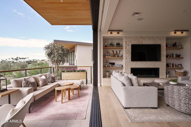 living room with a healthy amount of sunlight, wood ceiling, light hardwood / wood-style flooring, and a large fireplace