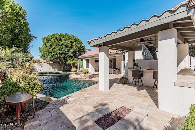 view of pool with a patio, exterior kitchen, ceiling fan, and a bar