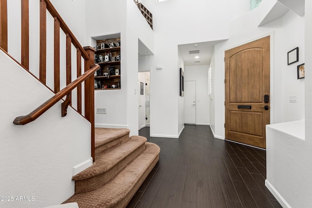 foyer entrance featuring dark wood-type flooring and a high ceiling