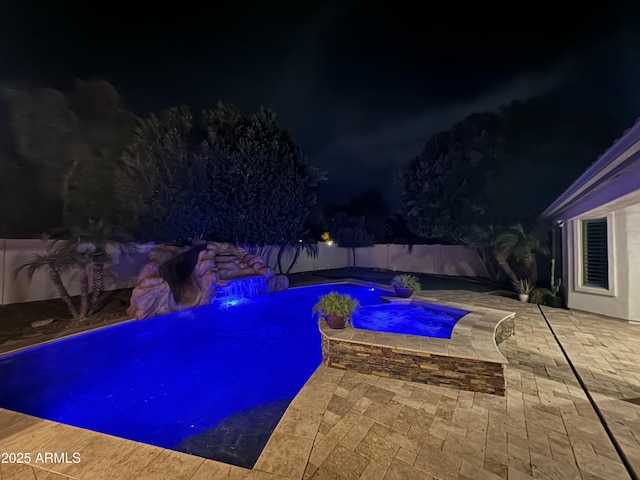 pool at twilight featuring a hot tub