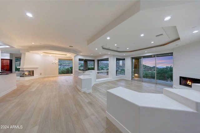 living room with a tray ceiling and light hardwood / wood-style floors