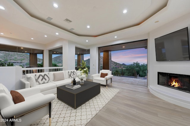 living room with a tray ceiling and light hardwood / wood-style floors