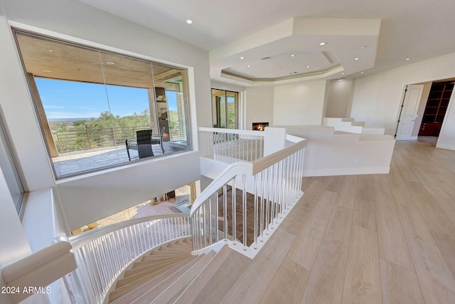 hall with a tray ceiling and light hardwood / wood-style flooring