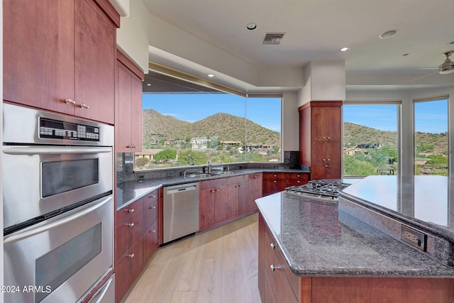 kitchen featuring sink, appliances with stainless steel finishes, a mountain view, light hardwood / wood-style floors, and backsplash