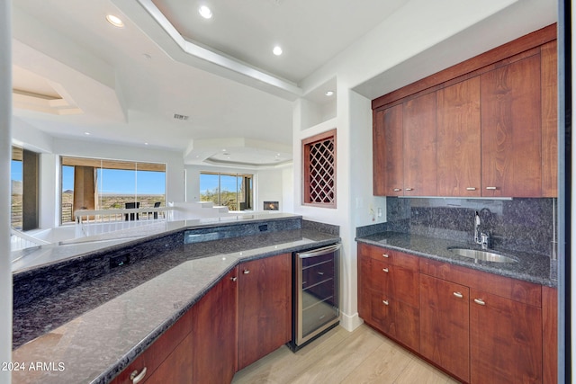 kitchen featuring wine cooler, sink, and dark stone countertops