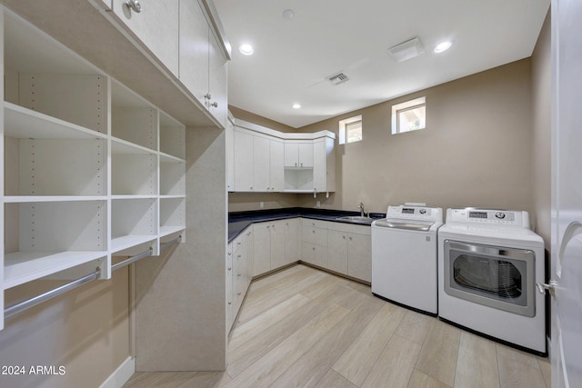 clothes washing area with sink, washer and clothes dryer, and light hardwood / wood-style flooring