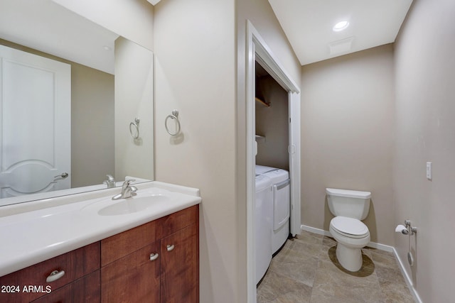 bathroom with vanity, washer and clothes dryer, and toilet