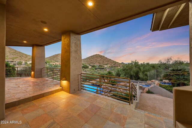 pool at dusk with an outdoor fire pit, a mountain view, and a patio