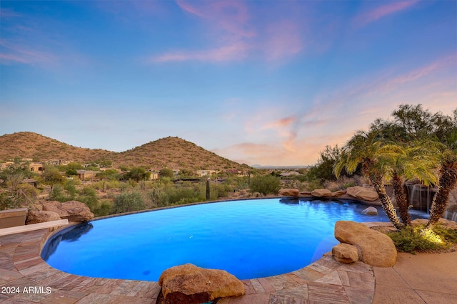 pool at dusk featuring a mountain view and a patio area