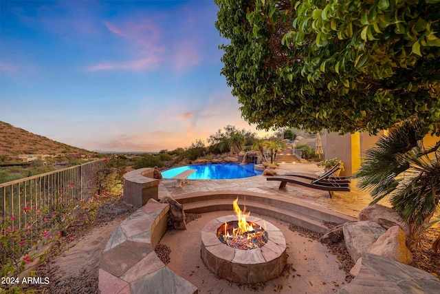 pool at dusk featuring a mountain view and a fire pit