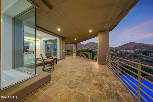 patio terrace at dusk featuring a balcony and a mountain view