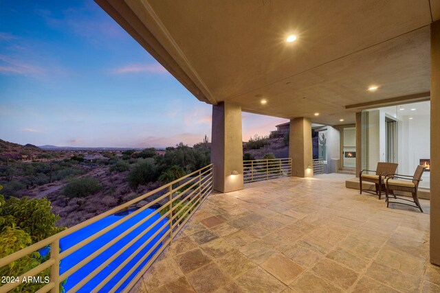 patio terrace at dusk featuring a balcony