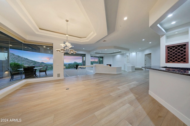 interior space featuring an inviting chandelier, a mountain view, a raised ceiling, and light wood-type flooring