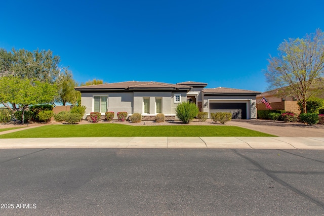 prairie-style home with stucco siding, an attached garage, driveway, and a front lawn