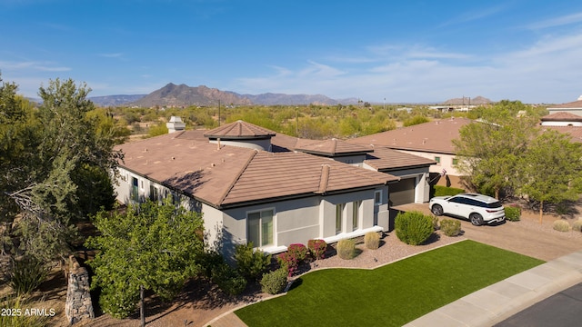 view of front of home with a front lawn, stucco siding, an attached garage, driveway, and a mountain view