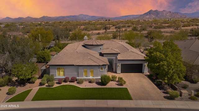 view of front of property featuring a tiled roof, a mountain view, driveway, an attached garage, and a front yard