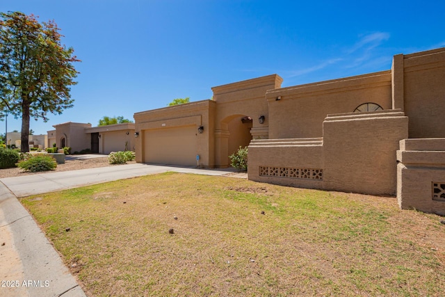 southwest-style home with a front lawn, an attached garage, concrete driveway, and stucco siding