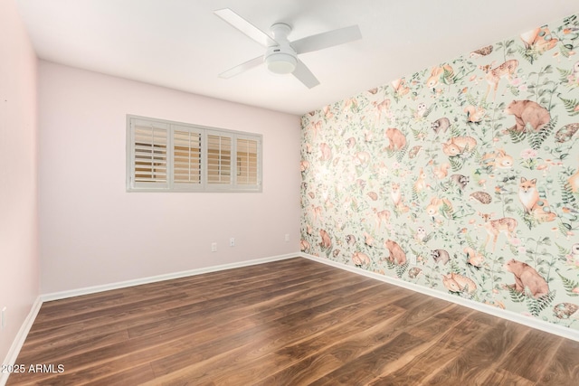spare room featuring a ceiling fan, baseboards, wallpapered walls, and wood finished floors