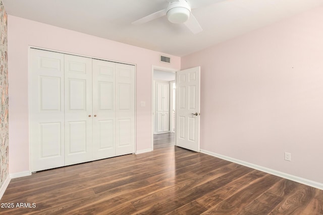 unfurnished bedroom featuring dark wood-style flooring, baseboards, visible vents, and a closet