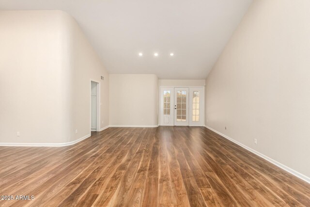empty room with high vaulted ceiling, french doors, baseboards, wood finished floors, and visible vents