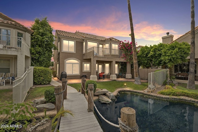 back of house with a balcony, a patio area, a tile roof, and fence