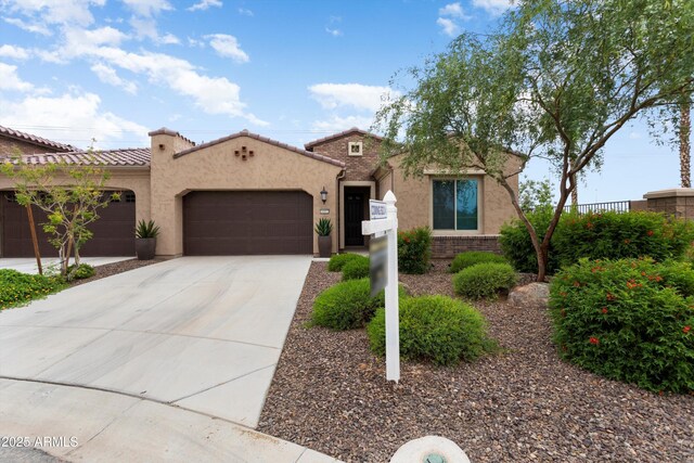16953 W Merrell St, Goodyear, AZ 85395 - mediterranean / spanish house with an attached garage, driveway, stucco siding, a tiled roof, and brick siding