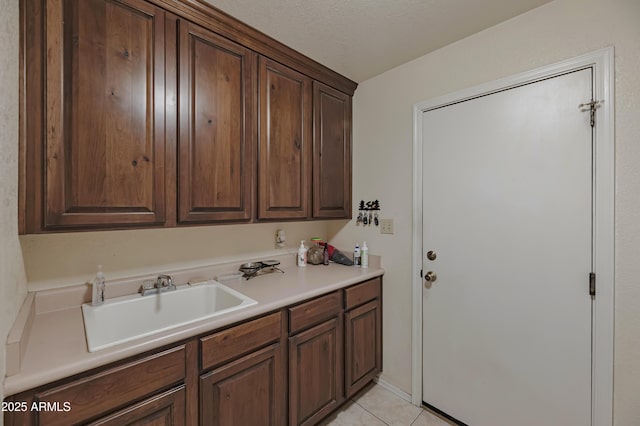clothes washing area with a sink and light tile patterned floors