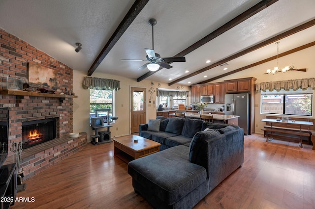 living area featuring light wood finished floors, a chandelier, ceiling fan, a brick fireplace, and recessed lighting
