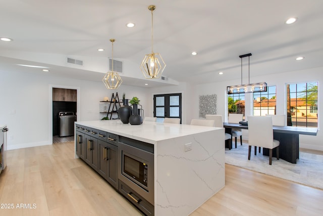 14012 N 57th Pl, Scottsdale, AZ 85254 - kitchen with light wood-style flooring, stainless steel microwave, french doors, recessed lighting, and a center island