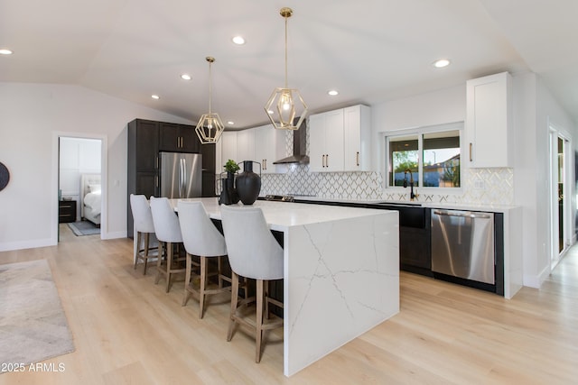 14012 N 57th Pl, Scottsdale, AZ 85254 - kitchen with stainless steel appliances, wall chimney range hood, light wood-style floors, a kitchen island, and a breakfast bar