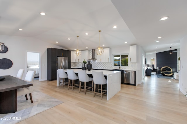 14012 N 57th Pl, Scottsdale, AZ 85254 - kitchen with appliances with stainless steel finishes, wall chimney range hood, lofted ceiling, a breakfast bar area, and decorative backsplash