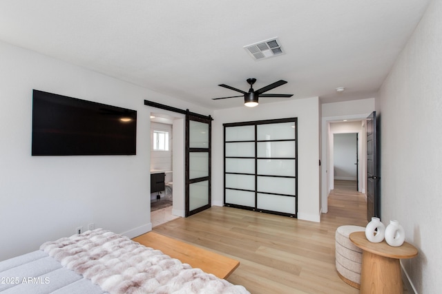 14012 N 57th Pl, Scottsdale, AZ 85254 - bedroom with a barn door, light wood-style flooring, ceiling fan, and ensuite bath