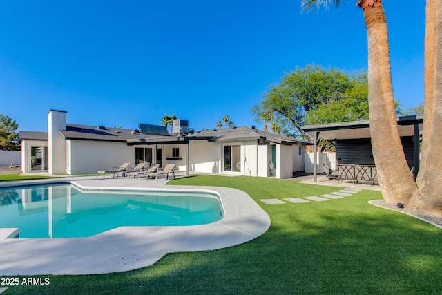 14012 N 57th Pl, Scottsdale, AZ 85254 - rear view of house featuring a patio, roof mounted solar panels, a lawn, an outdoor pool, and stucco siding