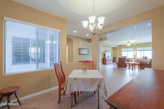 tiled dining room featuring ceiling fan with notable chandelier