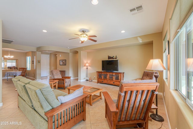 tiled living room featuring ceiling fan with notable chandelier