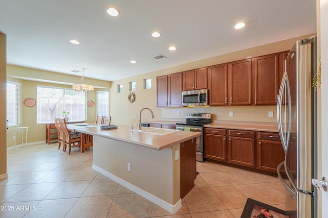 kitchen featuring sink, decorative light fixtures, a center island with sink, light tile patterned floors, and appliances with stainless steel finishes