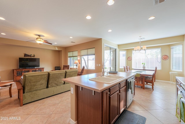 kitchen with light tile patterned floors, sink, hanging light fixtures, a healthy amount of sunlight, and a center island with sink