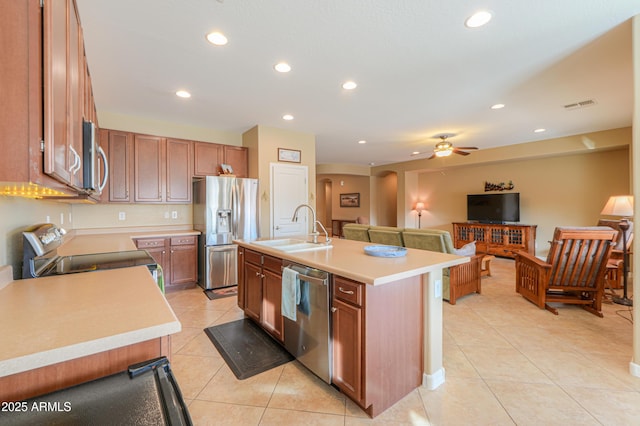 kitchen featuring sink, a center island with sink, light tile patterned floors, appliances with stainless steel finishes, and ceiling fan