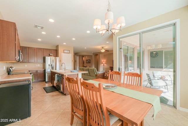 dining room with ceiling fan with notable chandelier, sink, and light tile patterned floors