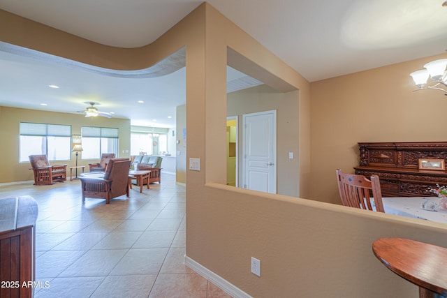 hallway featuring a healthy amount of sunlight, light tile patterned floors, and a chandelier