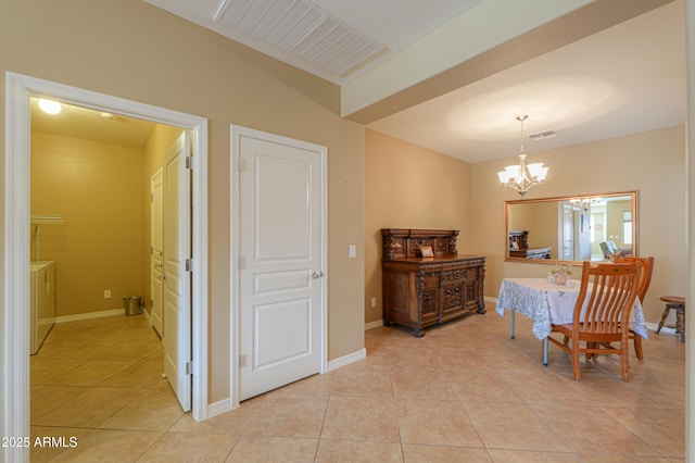 dining space with washer and dryer, light tile patterned floors, and an inviting chandelier