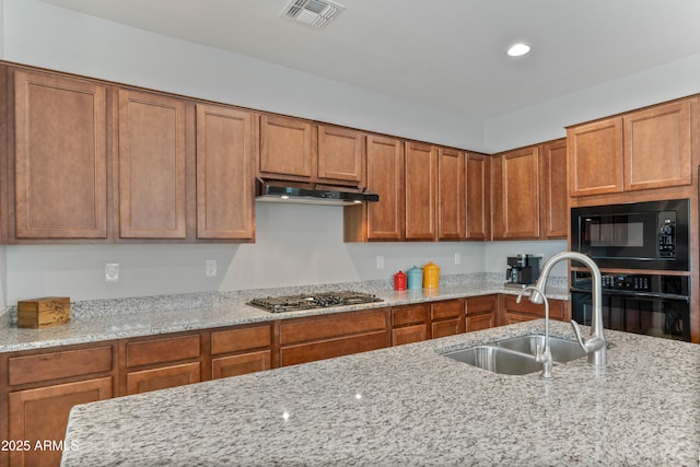 kitchen with light stone countertops, sink, and black appliances