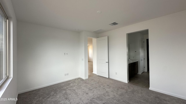 unfurnished bedroom with carpet and connected bathroom