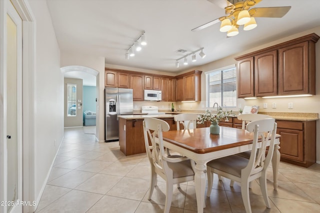 dining space featuring visible vents, arched walkways, light tile patterned flooring, baseboards, and ceiling fan