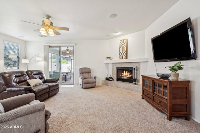 carpeted living area featuring visible vents, a ceiling fan, and a tile fireplace