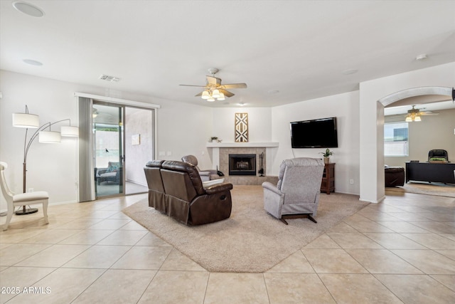 living area with arched walkways, visible vents, ceiling fan, and light tile patterned floors