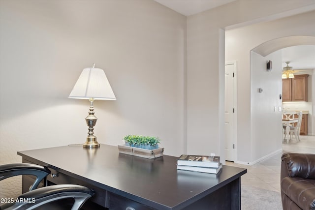 office space with light tile patterned floors, baseboards, arched walkways, and ceiling fan