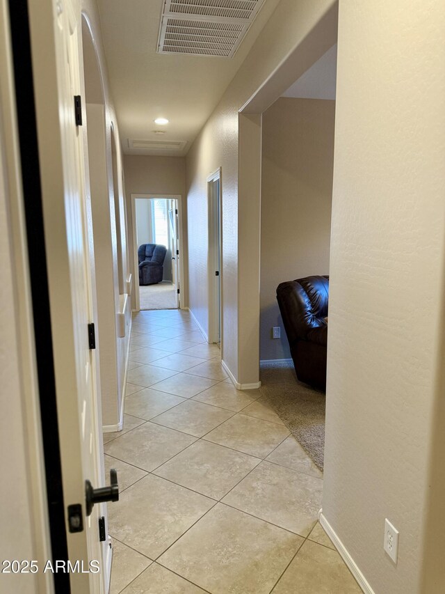 hall with light tile patterned floors, visible vents, and baseboards