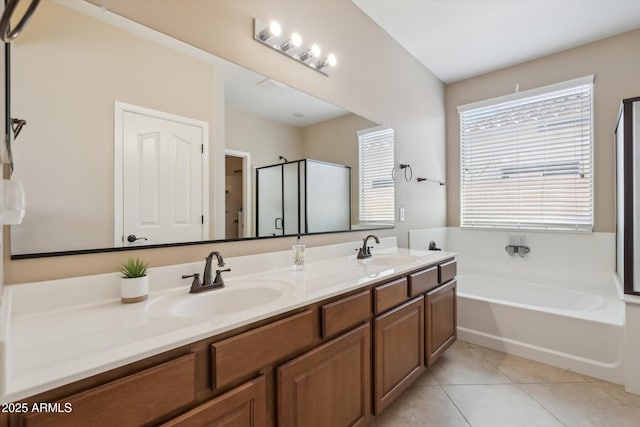 bathroom featuring tile patterned flooring, double vanity, a bath, and a sink